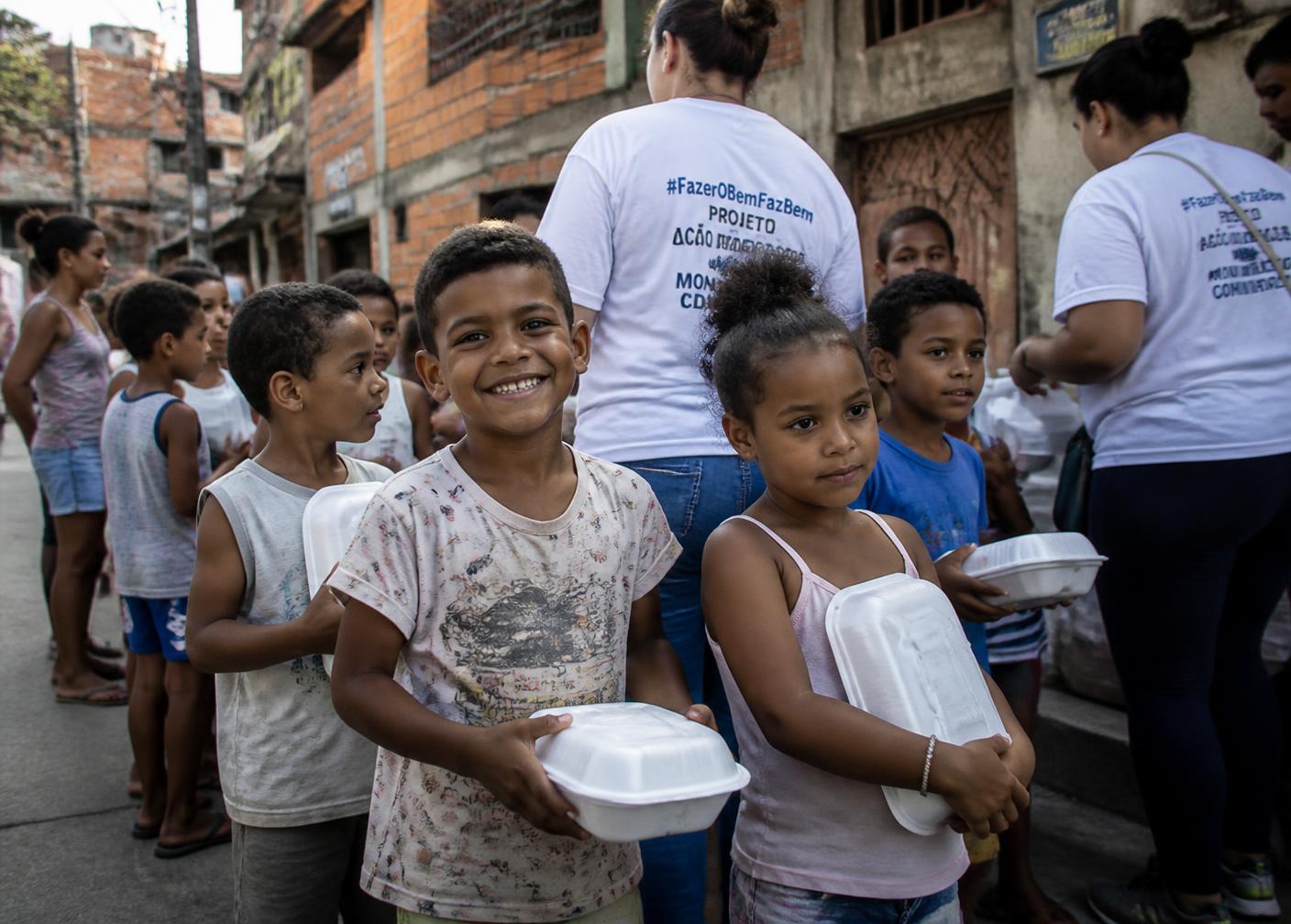 Crianças recebendo refeição em comunidade