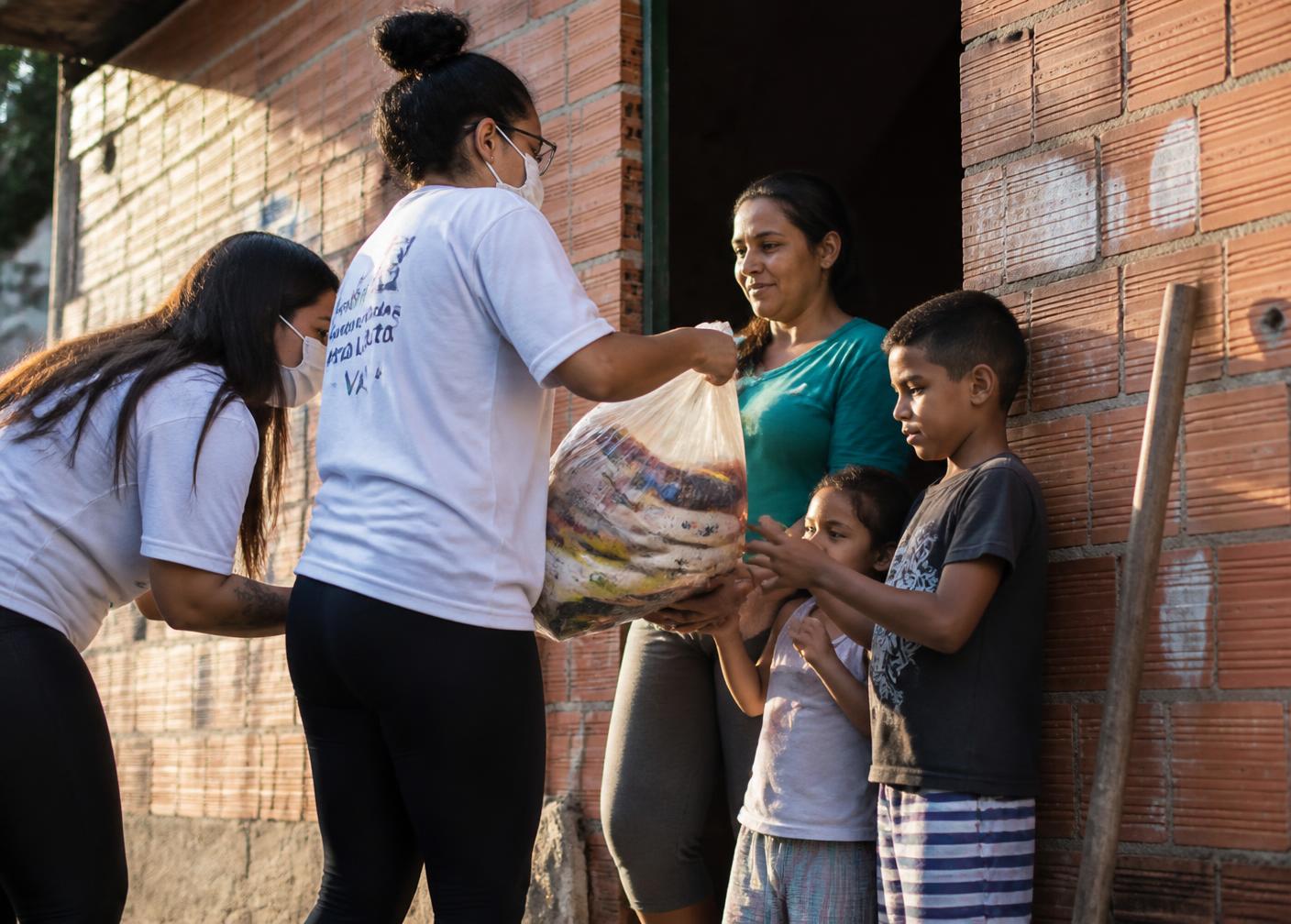 Voluntárias entregando alimentos a uma família em comunidade